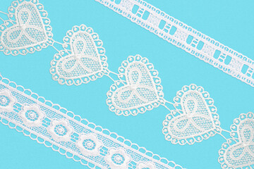 White laces with flowers and hearts on blue background isolated diagonally