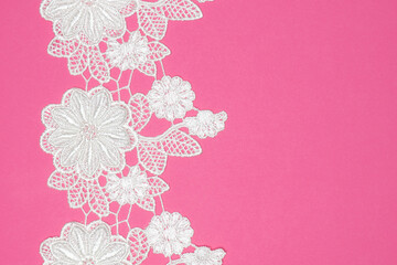 White laces with flowers and leaves on pink background isolated vertically