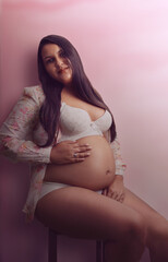 Pregnant latina portrait in underwear, cloudy rose background 