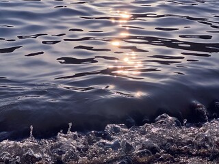 Sea wave sparkling blue water background. Sun reflection in sea water in beach at summer evening.