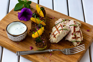 Grilled chicken or turkey breast with fresh vegetable salad on a white plate over dark green slate, stone or concrete vegetable.