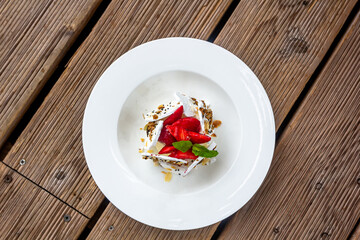 Sweet dessert, Pavlov's cake with butter cream and strawberries. Soft focus background, a place for text