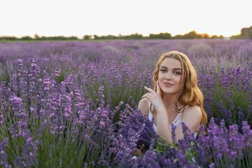 Fototapeta na wymiar Girl in a lavender field. Woman in a field of lavender flowers at sunset in a white dress. France, Provence.