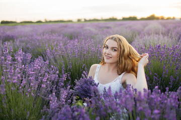Fototapeta na wymiar Girl in a lavender field. Woman in a field of lavender flowers at sunset in a white dress. France, Provence.