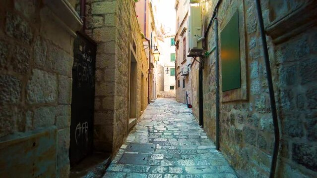 Handheld shot of the famous narrow alley of Dubrovnik in the old town, Croatia. Ancient and narrow path with stone architecture. A UNESCO World Heritage Site. A famous tourist destination. 4K UHD