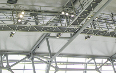 Ceiling with bright lighting in a modern warehouse, shopping center building, airport or other commercial real estate object. Directional LED lights on rails under the ceiling