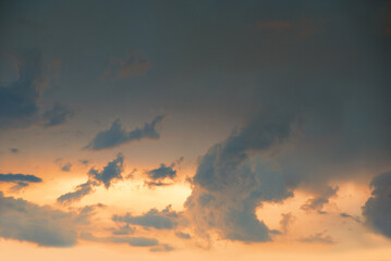 dark slate blue sky with floating clouds and yellow light after thunderstorm