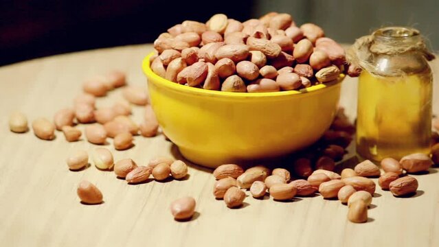 Whole peanut and peanut oil on table, eatable groundnut oil,peanuts in wooden bowl with canola oil,selective focus