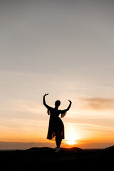 silhouette of a girl with raised hands at sunset. photo at the quarry. breathtaking view. ballerina pose
