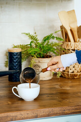 Closeup view of hand pouring coffee in a cup