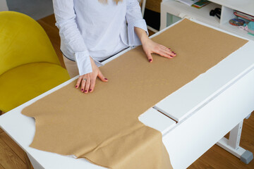 Seamstress puts piece of fabric on table. Fashion designer at tailor workplace. Dressmaking process