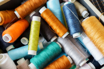 Background of many colorful spools of thread closeup. Sewing hobby concept. Pile of threads bobbins