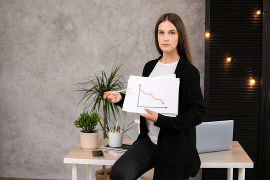 Young woman holding a sign with a decreasing statistics arrow symbol