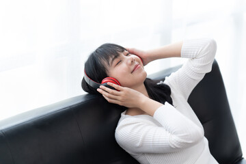 Happy young woman using smartphone at home sitting on soft couch, she is using a smartphone and texting, technology and communication concept.