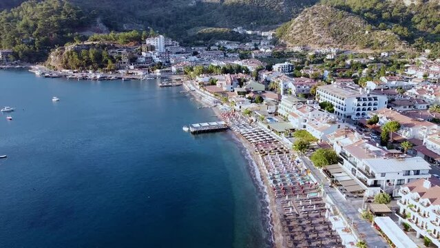 Drone view of seaside pier and beach in resort village Turunc in Turkey. Touristic resort town surrounded by mountains.