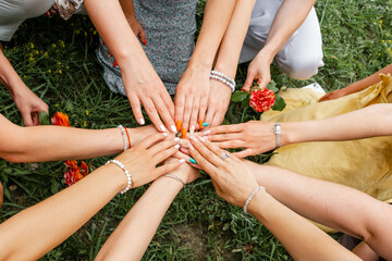 Group of people stacking hands together. Female models joining hands in a circle. Many hands together: group of people joining hands. Multiracial group of friends in stack. Teamwork