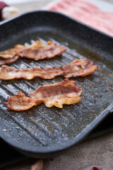 Bacon Being Cooked in grill frying pan Skillet at domestic kitchen
