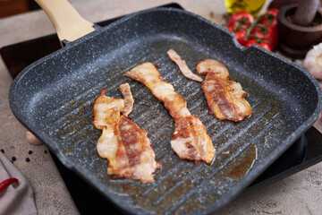 Bacon Being Cooked in grill frying pan Skillet at domestic kitchen