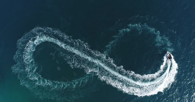 Aerial top view of a white pleasure boat on a summer day. Powerboat turn loop eight on the sea making metaverse infinity future concept. 