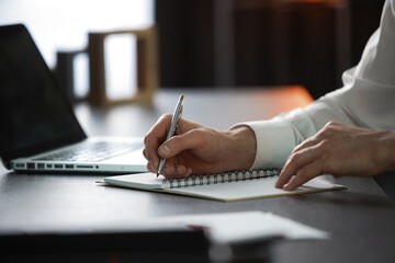 Close-up of male hand making notes, planning new appointments information in organizer personal paper planner at desk.