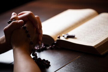 Christianity theme – prayer.  Christian woman with Bible praying with hands crossed keeping...
