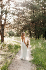 happy bride girl in a white light dress with a bouquet of dried flowers