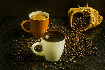 Two cups of coffee. Two flavors on black background. Top view.