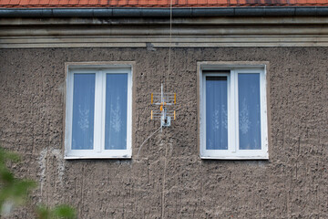 TV antenna mounted between two windows on the wall of a residential building.