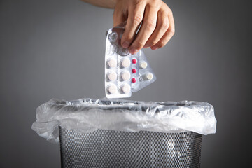 Male hand throws pills into the trash.