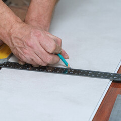 The worker marks the plastic panel with a pencil and tape measure or ruler. Selective focus