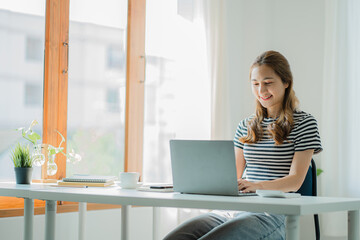 Asian young woman working with laptop computer and financial documents at home online study and...