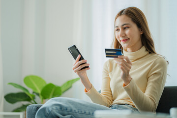 Beautiful Asian woman shopping online with credit card at home on Sopa online transaction. Concept...