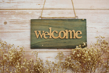 Welcome Sign with flower decoration on wooden background