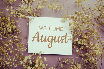 Welcome August text on paper card with flower decoration on purple background