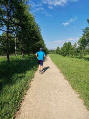Fototapeta premium a man runs in the park in summer, rear view. Sport lifestyle concept.