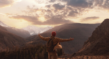 Adventure young man standing on top of cliff mountains background sunset. Lifestyle enjoying nature