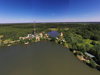 Fototapeta na wymiar a panoramic view of the green forest and the lake and the glampings standing on the shore on a sunny summer day taken from a drone