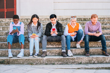 Fototapeta premium beautiful young people in casual clothes using mobile phone while sitting together on the stairs.