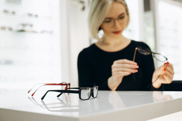 Woman choosing a pair of eyeglasses at optics store