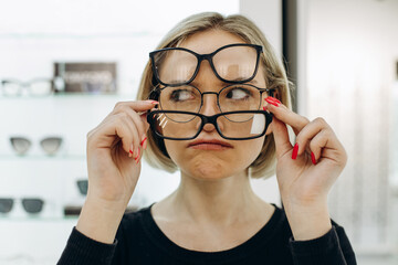 Woman choosing a pair of eyeglasses at optics store