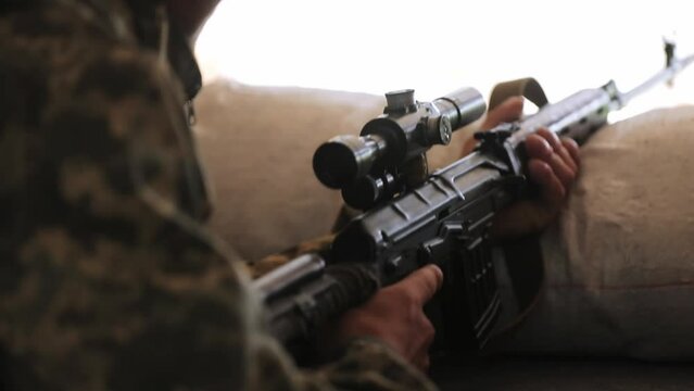 A Ukrainian sniper reloads a cartridge in the chamber of a Dragunov sniper rifle. a soldier loads a rifle. close-up. war in ukraine