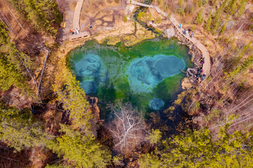 Turquoise blue geyser lake in autumn forest Altai mountains Russia. Aerial top view