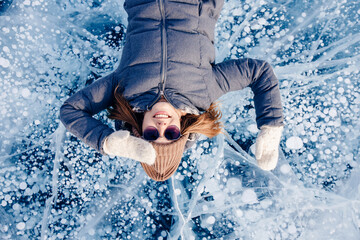 Tourist woman background ice with gas methane bubbles lake Baikal. Adventure winter travel top view