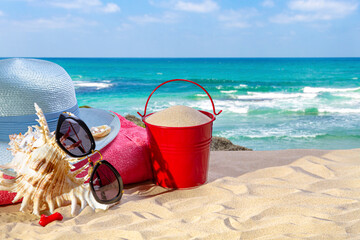 Beach accessories on a sandy beach against the backdrop of the sea. Summer background. Beach vacation concept.