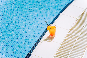 Tropical sparkling cocktail by the pool. The picture of glass with orange lemonade fruit cocktail...