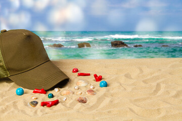 Khaki baseball cap with shells and corals on the sea beach.