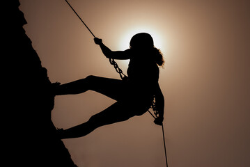 Silhouette of successful young female climber in the mountains Concept of self-improvement,...