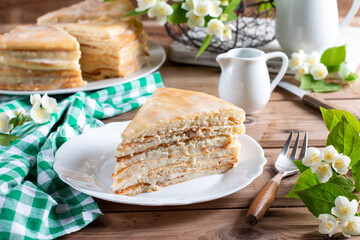 Homemade naked layered vanilla cake with whipped cream on a wooden table.