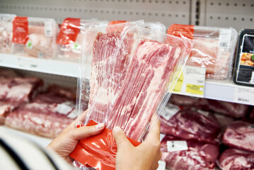 Woman hands with slice of pork meat at store