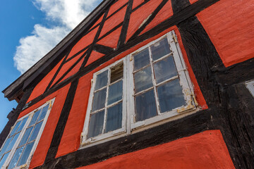 03-07-2022 Assens, Denmark - Old red house, black timber frame. Blue sky